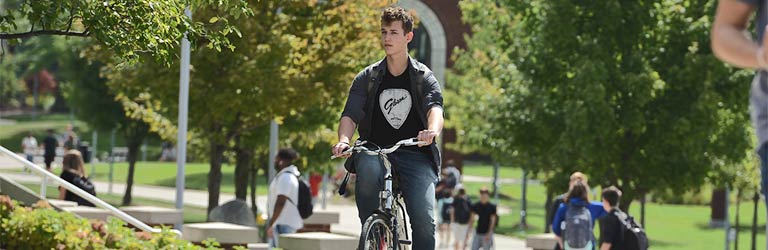 A student rides a bicycle through the center of campus