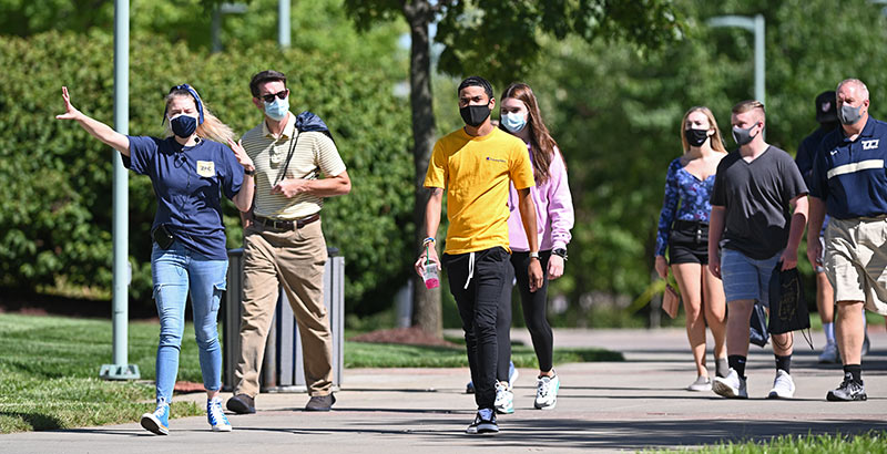An admissions tour guide leads a group near the Arts and Sciences Building