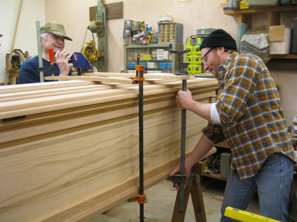 A son building a casket with his father in a work room