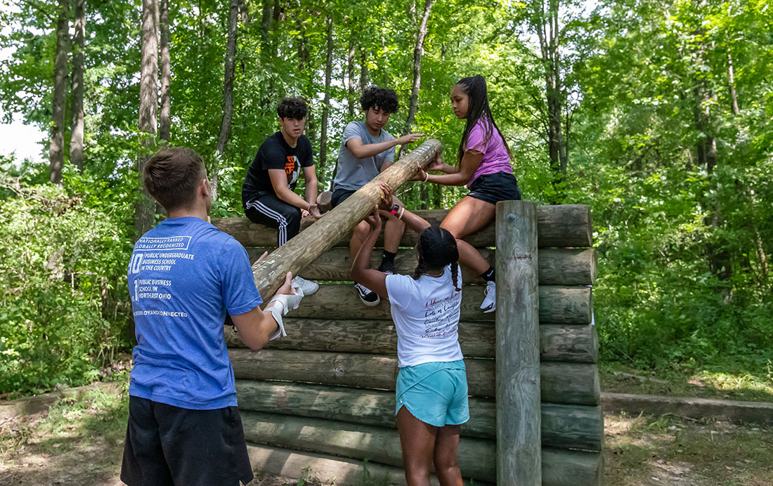CoB Summer Leadership Academy students carrying wood logs