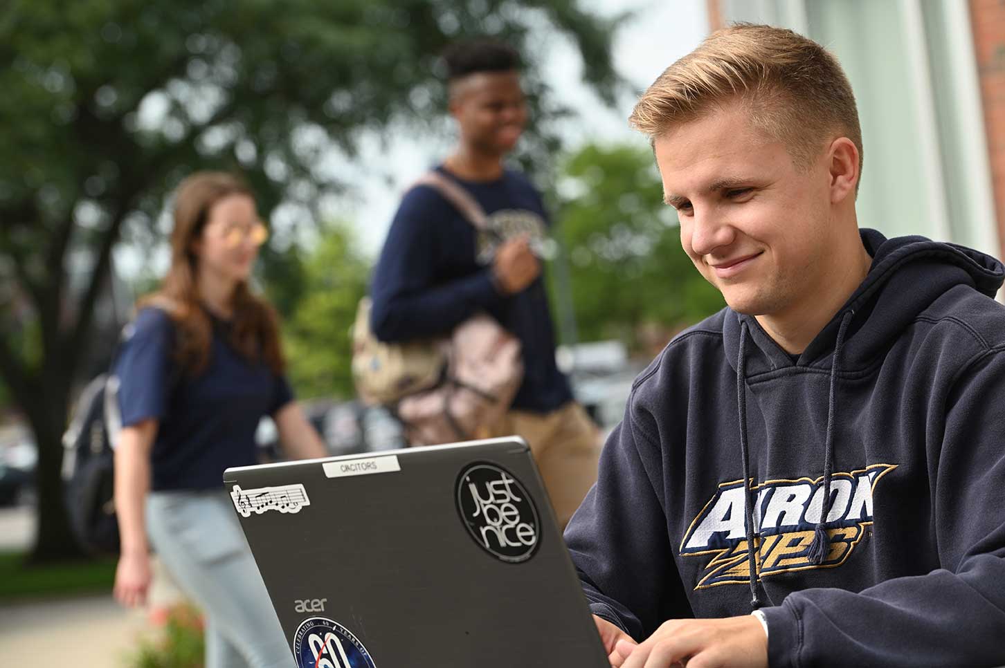 Male student working on laptop while outdoors on UA campus