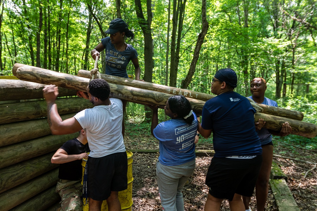 CoB Summer Leadership Academy students carrying wood logs