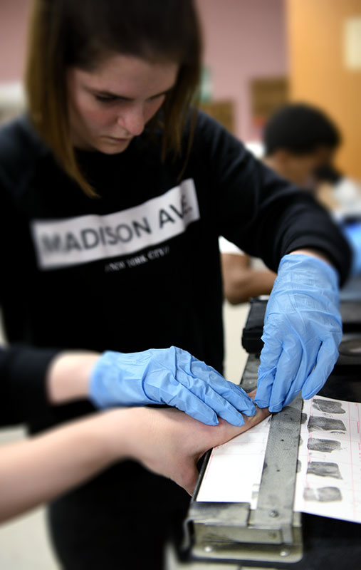A student practices fingerprinting in the criminal justice Forensics Lab at The University of Akron.