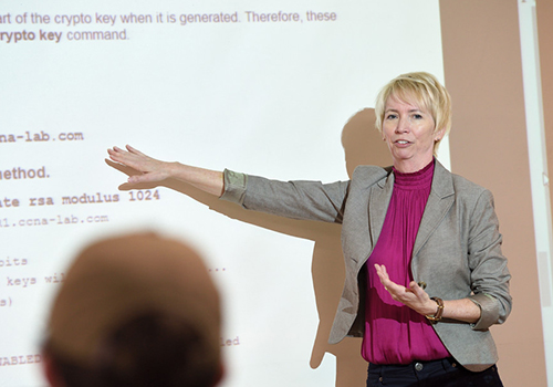A professor gestures near a whiteboard during a class