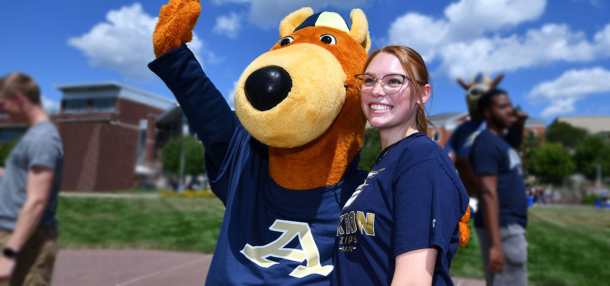A student with Zippy UA's mascot on the campus of The University of Akron