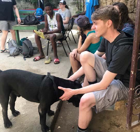 UA student Matt Waskey pets a dog while on his trip to Haiti