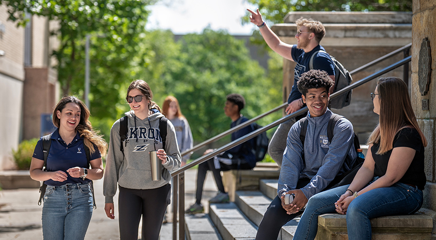 Happy UA students walking out of and in front of Buchtel Hall on The University of Akron campus.