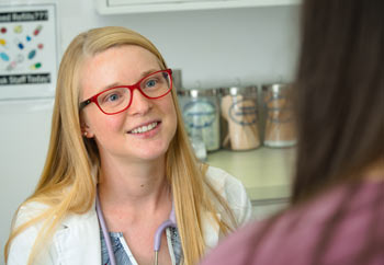 A nursing student smiles while chatting with a patient in a nursing clinic