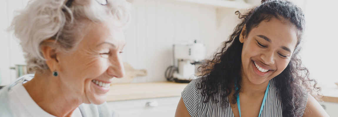 An older woman sitting with a younger social worker.