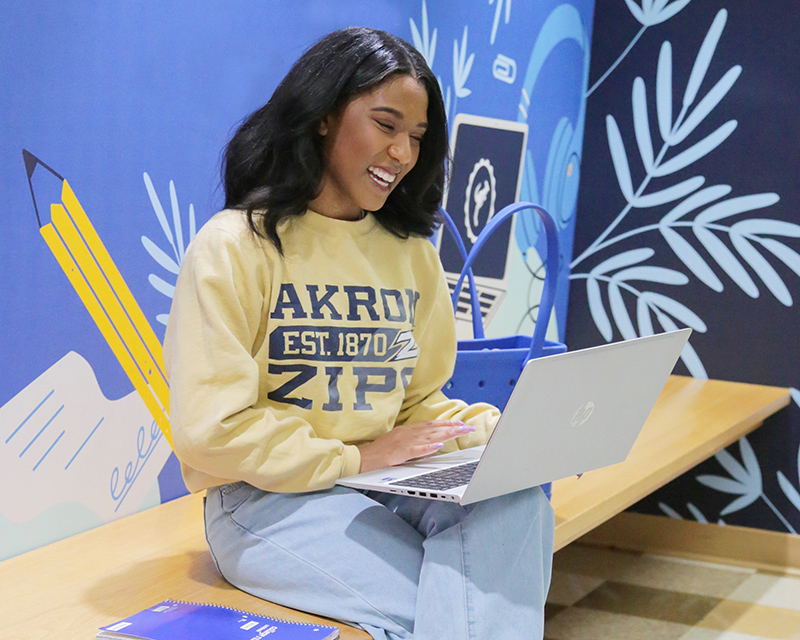 A smiling student studies on a laptop