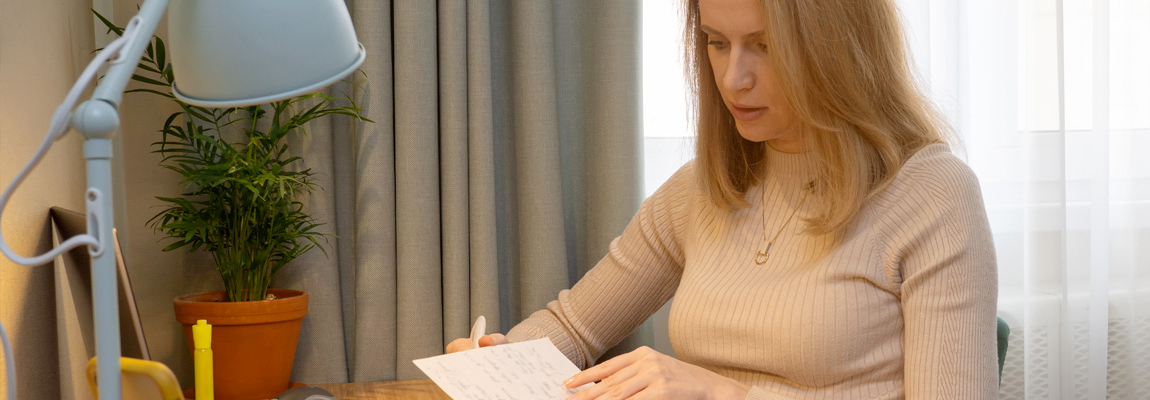 A woman sitting at a desk reviewing her notes from class.