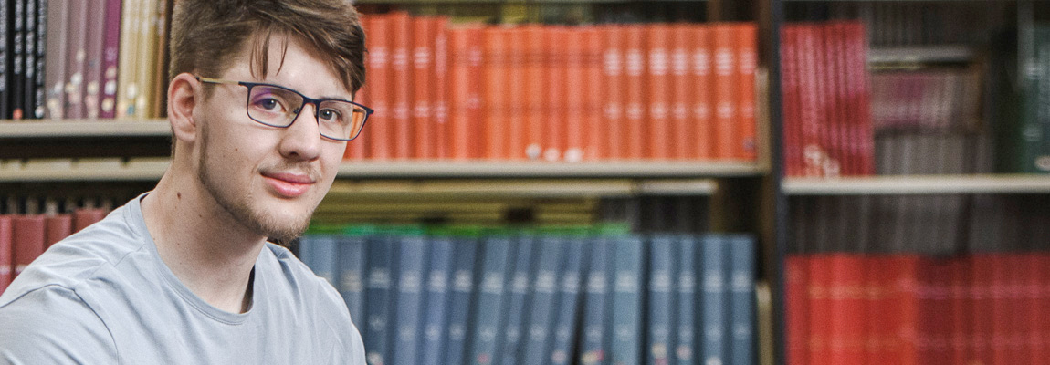 A man sitting in front of a bookshelf full of legal books.