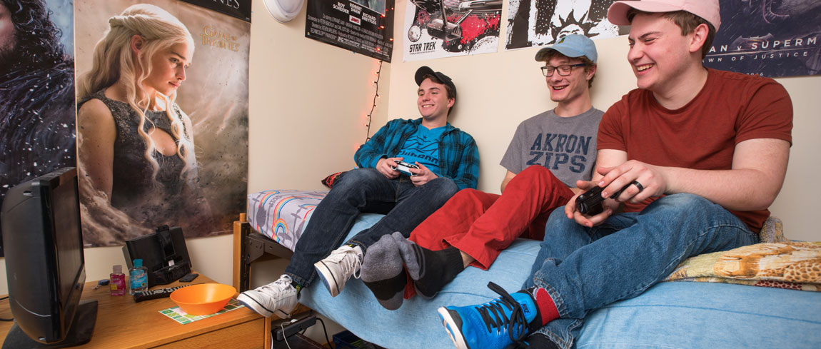 Three students playing video game in a UA college dorm